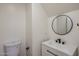 This bathroom features a clean white sink, vanity, and toilet with black fixtures, and a round, modern mirror at 942 S Ash Ave # 104, Tempe, AZ 85281