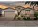Charming single-story home featuring a two-car garage, stone accents, and meticulously landscaped front yard at sunset at 9510 E Theia Dr, Mesa, AZ 85212