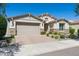 Charming single-story home featuring a two-car garage, stone accents, and meticulously landscaped front yard under blue skies at 9510 E Theia Dr, Mesa, AZ 85212