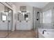 Bright bathroom featuring a double sink vanity, soaking tub, and glass enclosed shower with grey tiling at 1120 E Harbor View Dr, Gilbert, AZ 85234