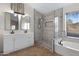 Bright bathroom featuring a double sink vanity, soaking tub, and glass enclosed shower with grey tiling at 1120 E Harbor View Dr, Gilbert, AZ 85234