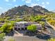 Aerial view of a Southwestern-style home, three-car garage, lush desert landscaping, and mountain views at 11398 E Desert Vista Rd, Scottsdale, AZ 85255
