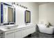 Bathroom featuring double sinks with framed mirrors, a soaking tub with a marble-style surround, and gray tile floors at 11426 E Quail Ln, Cave Creek, AZ 85331
