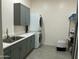Well-organized laundry room featuring stacked washer and dryer units, sleek gray cabinetry, and neutral tones at 11426 E Quail Ln, Cave Creek, AZ 85331
