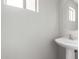 Half bathroom featuring a pedestal sink, a round mirror, and a small window at 11455 E Persimmon Ave, Mesa, AZ 85212