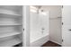 Bathroom with a shower-tub combo, white tile surround, and a built-in shelving unit at 11455 E Persimmon Ave, Mesa, AZ 85212
