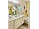 Bathroom with a dual-sink vanity, large mirror, decorative accents, and a soaking tub at 12027 W Morning Dove Dr, Sun City, AZ 85373