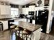 Well-lit kitchen featuring white cabinets, black appliances, and a center island with seating at 12027 W Morning Dove Dr, Sun City, AZ 85373