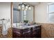 Elegant bathroom with double sinks, ornate dark wood cabinets, a decorative mirror, and accent tiling at 12210 N 67Th St, Scottsdale, AZ 85254