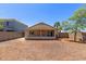 Spacious backyard featuring a covered patio and mature palm trees, enclosed by a block fence at 12438 W Flores Dr, El Mirage, AZ 85335