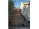 Narrow dirt backyard with overgrown bushes, a wooden fence, and a shed siding wall at 1363 E Clarendon Ave, Phoenix, AZ 85014