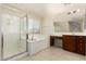 Bright bathroom showcasing a glass-enclosed shower, soaking tub, and vanity with dark wood cabinets at 14440 W Cholla St, Surprise, AZ 85379