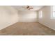 Large room with neutral walls, ceiling fan, window with shutters and carpeted floor at 14440 W Cholla St, Surprise, AZ 85379