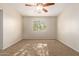 This cozy carpeted bedroom features a ceiling fan and a window offering natural light at 14440 W Cholla St, Surprise, AZ 85379