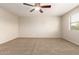 This cozy carpeted bedroom features a ceiling fan and a window offering natural light at 14440 W Cholla St, Surprise, AZ 85379