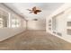 Bright, spacious living room featuring neutral walls, ceiling fans, and large windows for ample natural light at 14440 W Cholla St, Surprise, AZ 85379