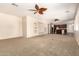 Bright, spacious living room featuring neutral walls, ceiling fans, with an open view into the kitchen at 14440 W Cholla St, Surprise, AZ 85379