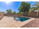 Backyard pool with stone deck, decorative rocks, and mature trees offering shade and tranquility at 14440 W Cholla St, Surprise, AZ 85379