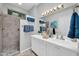 Bathroom featuring double sinks, white cabinetry, a walk-in shower, and blue towels at 15161 W Cactus Ridge Way, Surprise, AZ 85374