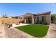 Beautiful backyard with lush green artificial turf, built in grill, and a cozy outdoor sitting area with fire pit at 1824 N Red Clf, Mesa, AZ 85207