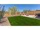 The backyard features artificial turf, a built-in grill, and a cozy sitting area with a fire pit surrounded by a metal fence at 1824 N Red Clf, Mesa, AZ 85207