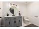 A bathroom features a gray vanity with a vessel sink, a round mirror, and a toilet at 2350 E Melrose St, Gilbert, AZ 85297