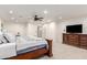 Bright main bedroom features a ceiling fan, an ensuite bathroom, and a dresser with a television on top at 2350 E Melrose St, Gilbert, AZ 85297