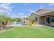 Lush backyard featuring a pool, seating area, grass, and mature landscaping with a covered patio at 26624 N 41St St, Cave Creek, AZ 85331
