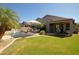 Expansive backyard with a pool, covered patio, and lush green lawn at 26624 N 41St St, Cave Creek, AZ 85331