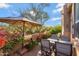 Outdoor patio with dining table, chairs, umbrella, plants, and desert landscape at 28990 N White Feather Ln # 185, Scottsdale, AZ 85262