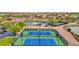 Aerial view of tennis courts and community park, pool, and playground with a lake and green space nearby at 30032 N Desert Willow Blvd, San Tan Valley, AZ 85143