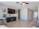 Bright living room with tiled flooring, neutral walls, a ceiling fan, and a large TV at 30560 W Weldon Ave, Buckeye, AZ 85396