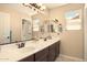 Spacious, neutral-toned bathroom features a double sink vanity with granite countertops, stylish light fixtures, and a large mirror at 31156 N 137Th Ln, Peoria, AZ 85383