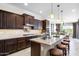 Gourmet kitchen features dark wood cabinets, granite countertops, island with seating and modern appliances at 31156 N 137Th Ln, Peoria, AZ 85383