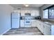 Efficient kitchen featuring plank flooring, white cabinetry, stainless steel sink, and window for light at 3209 W Charleston Ave, Phoenix, AZ 85053