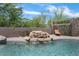 Backyard pool showcasing a serene rock waterfall feature surrounded by lush greenery and privacy fencing at 3812 N Barron --, Mesa, AZ 85207
