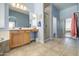 Bright bathroom with a large mirror, double sink vanity, walk-in shower, soaking tub, and tile flooring at 43302 W Bunker Dr, Maricopa, AZ 85138