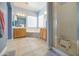Bright bathroom featuring a walk-in glass shower, double sink vanity, soaking tub, and tiled floor at 43302 W Bunker Dr, Maricopa, AZ 85138