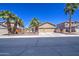 Well-maintained single-story home with a three car garage, palm trees, and desert landscaping at 43302 W Bunker Dr, Maricopa, AZ 85138