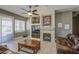 Well-lit living room with tile floors, a modern ceiling fan, fireplace and comfortable brown leather seating at 43302 W Bunker Dr, Maricopa, AZ 85138