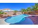 A private backyard oasis features a pristine pool, rock waterfall, and mature landscaping with palm trees at 43302 W Bunker Dr, Maricopa, AZ 85138