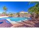 Backyard pool area featuring a small waterfall, mature palm trees, and privacy fence at 43302 W Bunker Dr, Maricopa, AZ 85138
