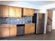 Modern kitchen with wood cabinets, stainless steel fridge and mosaic backsplash at 4517 S Grandview Ave, Tempe, AZ 85282