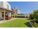 Large backyard featuring artificial grass, patio, and colorful flower beds at 630 E Jensen St # 116, Mesa, AZ 85203