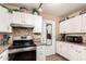 Modern kitchen featuring stainless steel range, microwave, tile backsplash, and white cabinets at 630 E Jensen St # 116, Mesa, AZ 85203