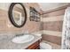 Cozy bathroom featuring custom brown and white tiled walls, dark wood vanity, and granite countertop at 6312 N 41St Ave, Phoenix, AZ 85019