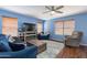 Cozy living room features comfortable seating, a ceiling fan, a large TV, and wood floors throughout at 6462 E Raftriver St, Mesa, AZ 85215