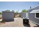 Rear view of the home's backyard with gravel landscape, AC unit and storage sheds at 9733 E Baywood Ave, Mesa, AZ 85208