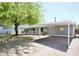 Side view of a gray home with a carport, desert landscaping and a large tree at 9733 E Baywood Ave, Mesa, AZ 85208