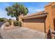 Front exterior view of house featuring a large garage door, mature tree, and desert landscape at 1023 E Sahuaro Dr, Phoenix, AZ 85020